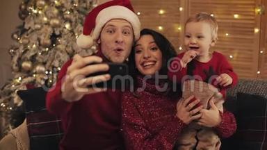 幸福的一家人在家里在圣诞树背景上自拍。 圣诞新年圣诞庆祝概念